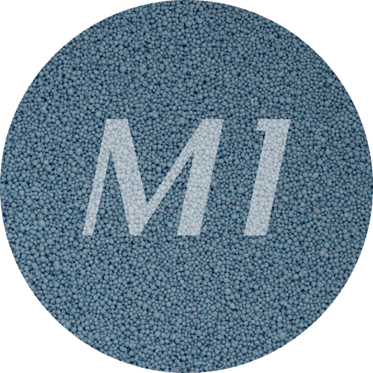 Kleurstaal van blauw kaarsenzand met fijne waxparels en subtiel M1-logo op de achtergrond.