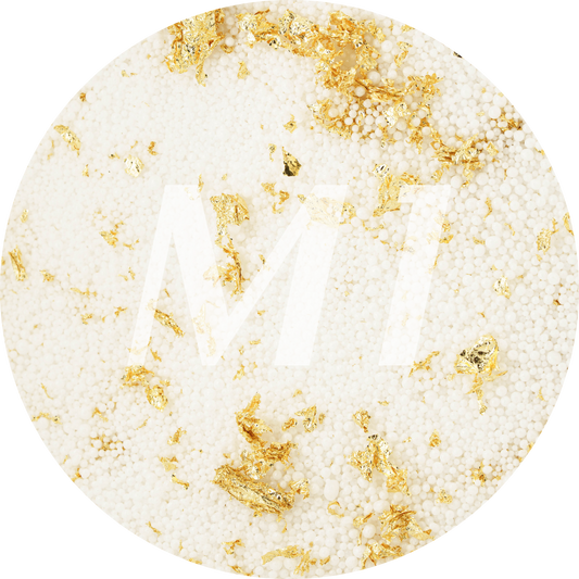 Kleurstaal van wit kaarsenzand met gouden glinsterflakes en subtiel M1-logo op de achtergrond.
