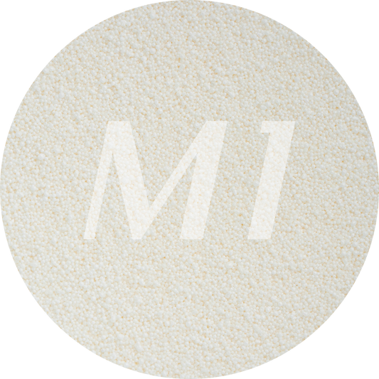 Kleurstaal van gebroken wit kaarsenzand met fijne waxparels en subtiel M1-logo op de achtergrond.