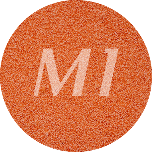 Kleurstaal van oranje kaarsenzand met fijne waxparels en subtiel M1-logo op de achtergrond.