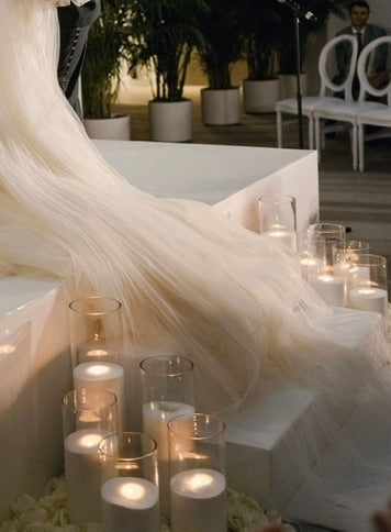 Romantische wedding decoratie met kaarsen in glazen cilinders naast bruidsjurk