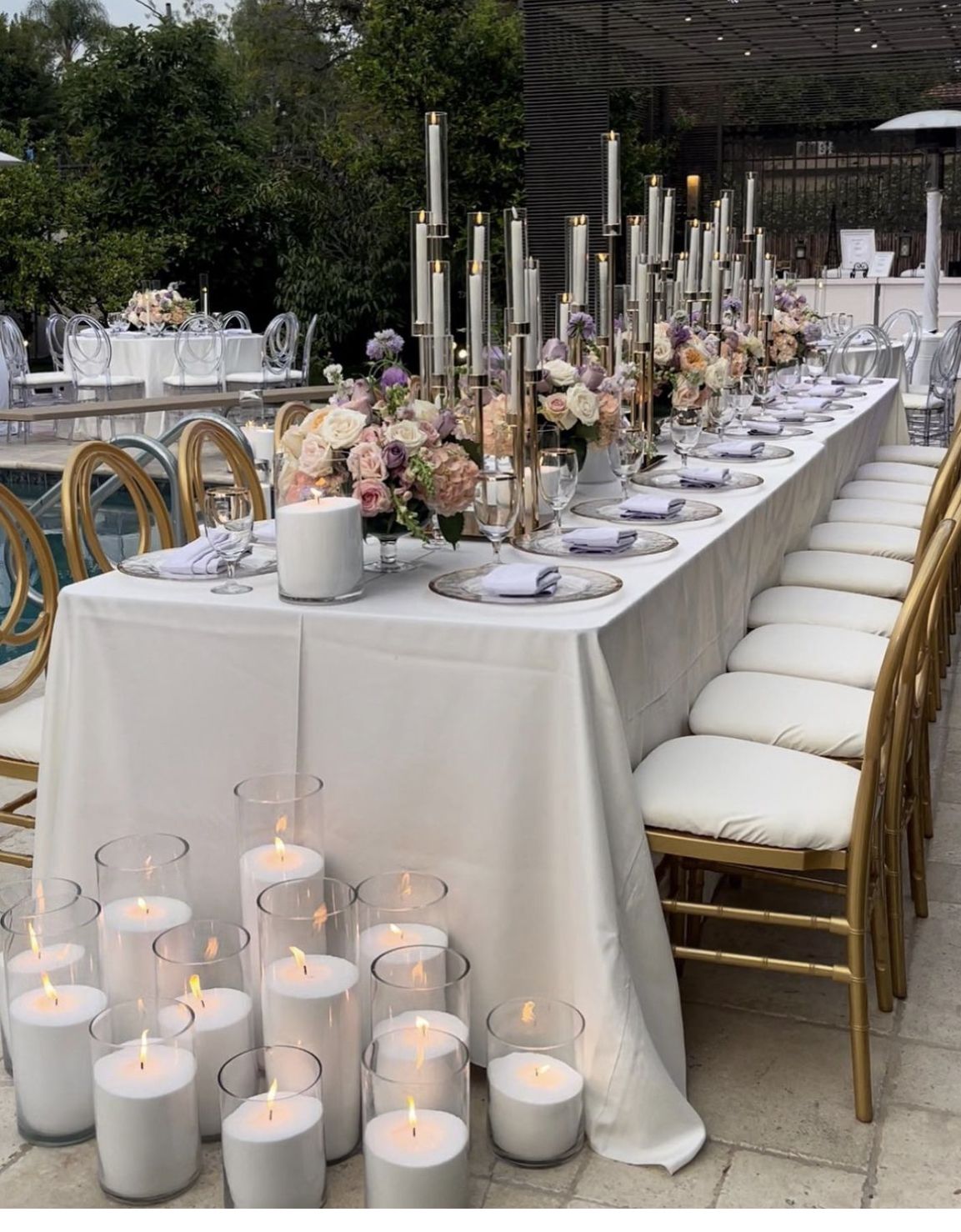 Luxe wedding tafeldecoratie met bloemen, kaarsen in glazen cilinders en lange dinertafel
