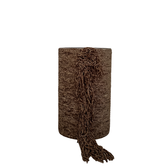 Cilindervormige kaarsenhouder met bruine stoffen bekleding en decoratieve franjes aan de voorzijde, op transparante achtergrond.