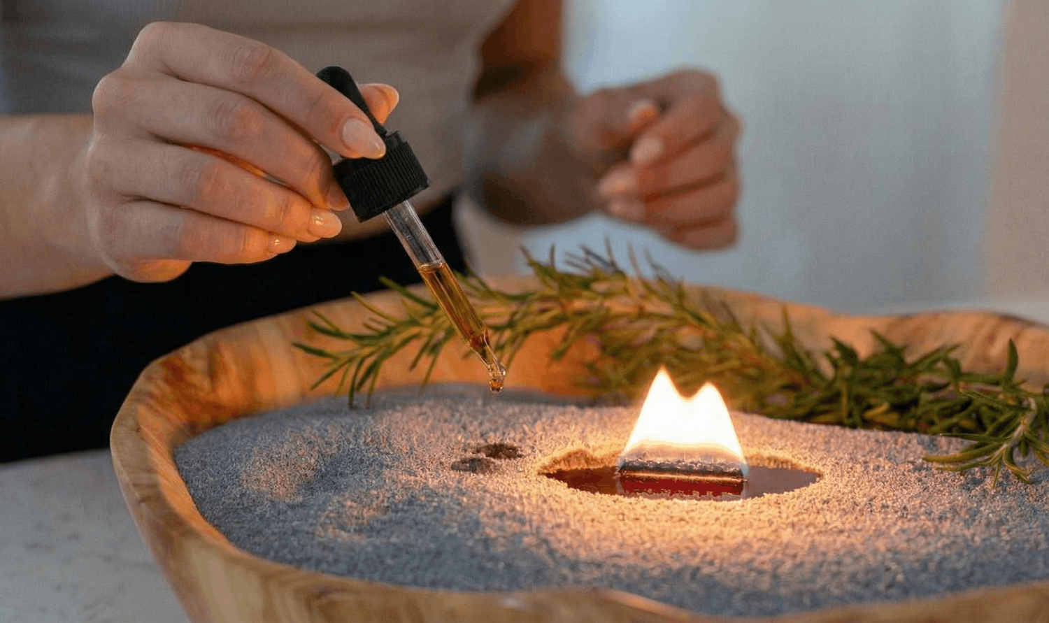 Close-up van kaarsenzand met brandende lont terwijl geur olie wordt toegevoegd met een pipet voor extra geur en sfeer.