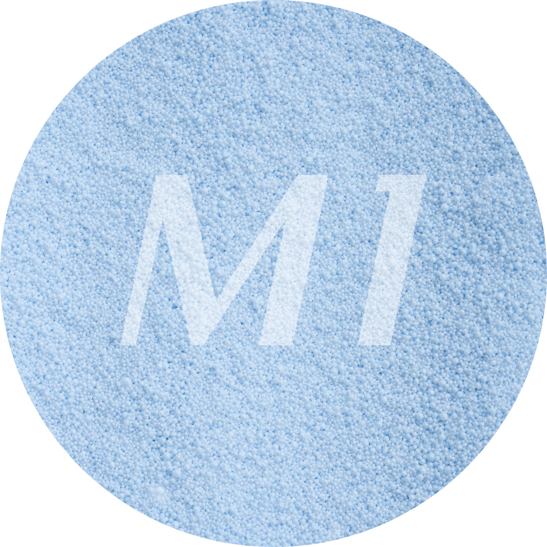 Kleurstaal van licht blauw kaarsenzand met fijne waxparels en subtiel M1-logo op de achtergrond.