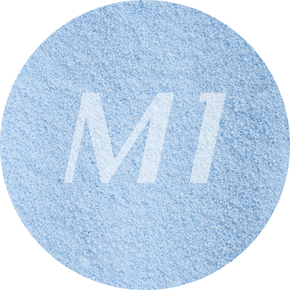 Kleurstaal van licht blauw kaarsenzand met fijne waxparels en subtiel M1-logo op de achtergrond.