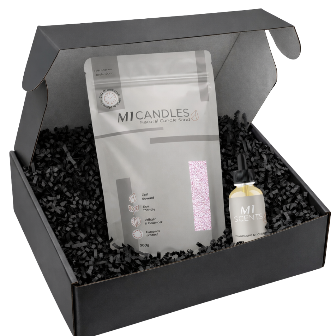 Open zwarte giftbox met M1 Candles natural candle sand in hersluitbare verpakking en M1 Scents Champagne & Roses geurolie, gepresenteerd in zwart papieren opvulmateriaal als luxe cadeauset.