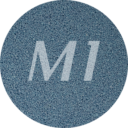 Kleurstaal van blauw kaarsenzand met fijne waxparels en subtiel M1-logo op de achtergrond.