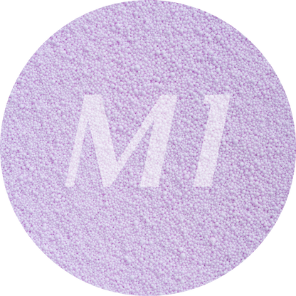 Kleurstaal van lilac kaarsenzand met fijne waxparels en subtiel M1-logo op de achtergrond.