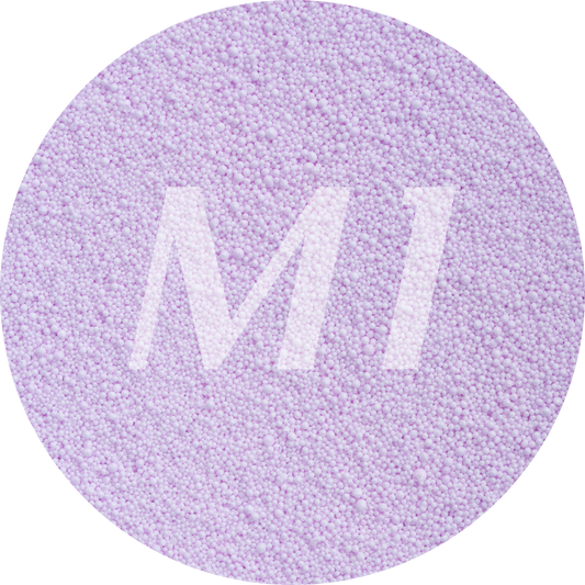 Kleurstaal van lilac kaarsenzand met fijne waxparels en subtiel M1-logo op de achtergrond.