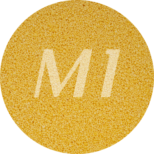 Kleurstaal van geel kaarsenzand met fijne waxparels en subtiel M1-logo op de achtergrond.