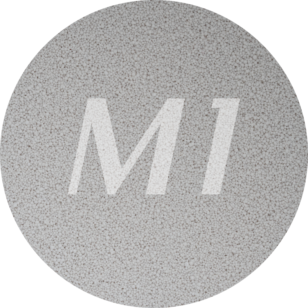 Kleurstaal van licht grijs kaarsenzand met fijne waxparels en subtiel M1-logo op de achtergrond.