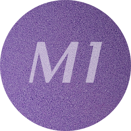 Kleurstaal van paars kaarsenzand met fijne waxparels en subtiel M1-logo op de achtergrond.