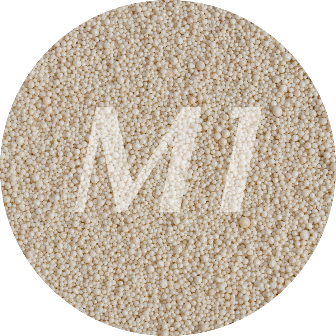 Kleurstaal van beige kaarsenzand met fijne waxparels en subtiel M1-logo op de achtergrond.