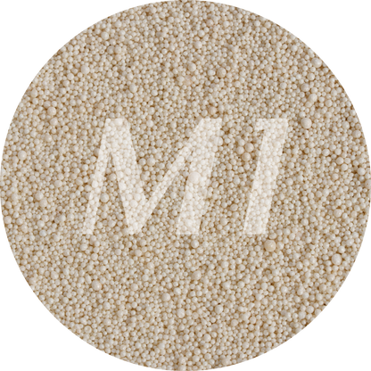 Kleurstaal van beige kaarsenzand met fijne waxparels en subtiel M1-logo op de achtergrond.