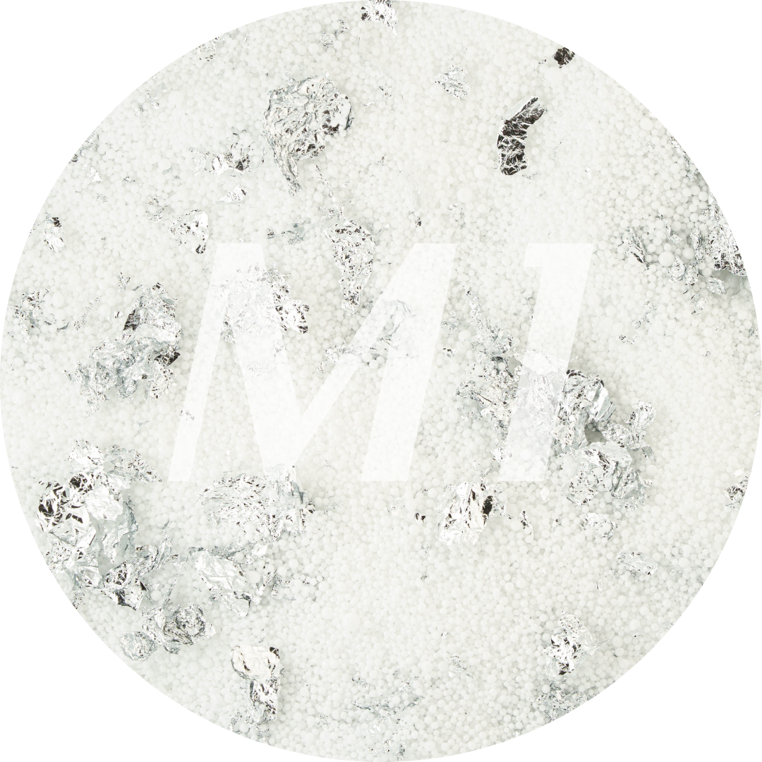 Kleurstaal van wit kaarsenzand met zilveren glinsterflakes en subtiel M1-logo op de achtergrond.