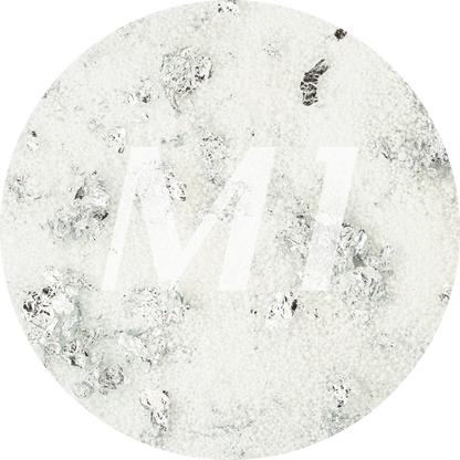 Kleurstaal van wit kaarsenzand met zilveren glinsterflakes en subtiel M1-logo op de achtergrond.