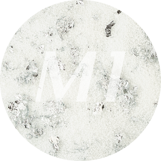 Kleurstaal van wit kaarsenzand met zilveren glinsterflakes en subtiel M1-logo op de achtergrond.