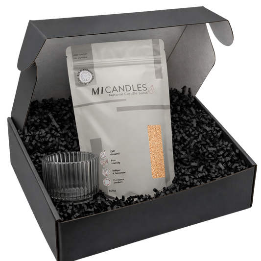 Zwarte luxe giftbox met M1 Candles candle sand in hersluitbare verpakking, glazen kaarshouder en zwarte papieren opvulsnippers, stijlvol gepresenteerd als complete cadeauset.
