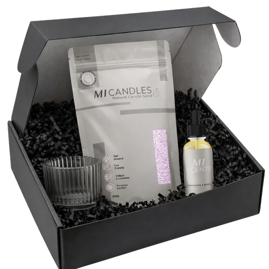 Zwarte luxe giftbox met M1 Candles candle sand in hersluitbare verpakking, glazen kaarshouder en zwarte papieren opvulsnippers, stijlvol gepresenteerd als complete cadeauset.