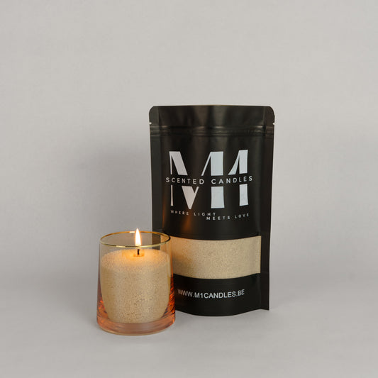 Verpakking van M1 Scented Candles kaarsenzand in een zwarte zak met logo, naast een glazen houder gevuld met brandend kaarsenzand.